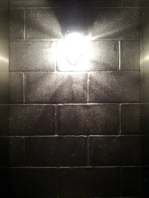 A bright light on a dark cinder block wall